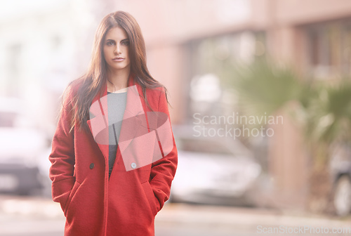 Image of Look fab this fall. Portrait of a gorgeous young woman in a red winter coat standing in an urban setting.