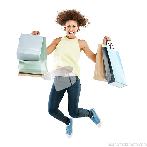 Image of Shopping spree frenzy. Studio portrait of an excited young woman carrying shopping bags and jumping for joy against a white background.