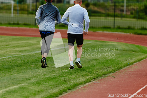 Image of An inspiring and active elderly couple showcase their dedication to fitness as they running together on a lush green field, captured in a close-up shot of their legs in motion.