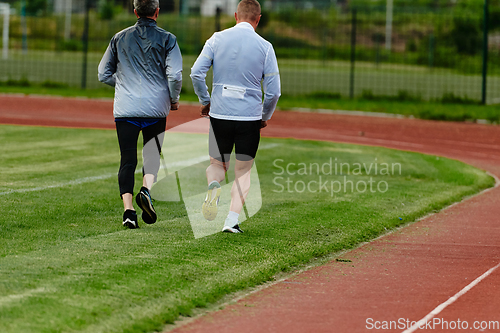 Image of An inspiring and active elderly couple showcase their dedication to fitness as they running together on a lush green field, captured in a close-up shot of their legs in motion.