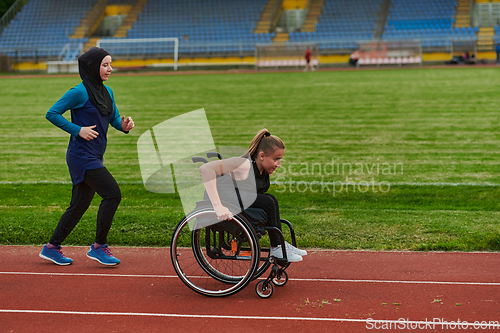 Image of A Muslim woman in a burqa running together with a woman in a wheelchair on the marathon course, preparing for future competitions.