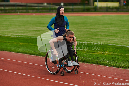 Image of A Muslim woman in a burqa running together with a woman in a wheelchair on the marathon course, preparing for future competitions.