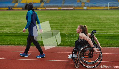 Image of A Muslim woman in a burqa running together with a woman in a wheelchair on the marathon course, preparing for future competitions.