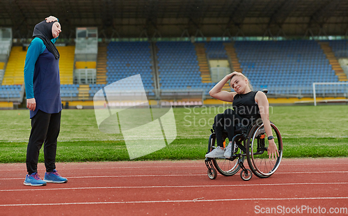 Image of Two strong and inspiring women, one Muslim in a burka and the other in a wheelchair stretching necks while on the marathon course