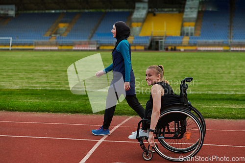 Image of A Muslim woman in a burqa running together with a woman in a wheelchair on the marathon course, preparing for future competitions.