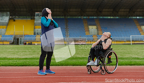 Image of Two strong and inspiring women, one Muslim in a burka and the other in a wheelchair stretching necks while on the marathon course