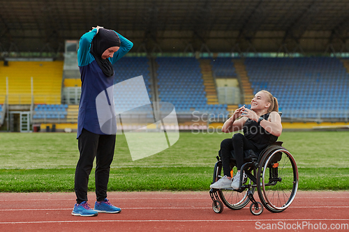 Image of Two strong and inspiring women, one Muslim in a burka and the other in a wheelchair stretching necks while on the marathon course