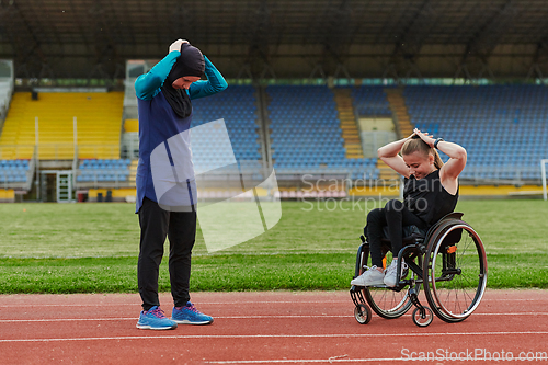 Image of Two strong and inspiring women, one Muslim in a burka and the other in a wheelchair stretching necks while on the marathon course