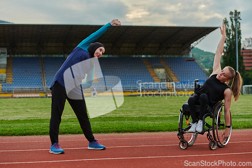 Image of Two strong and inspiring women, one a Muslim wearing a burka and the other in a wheelchair stretching and preparing their bodies for a marathon race on the track