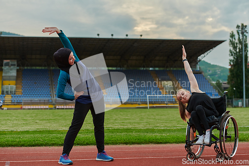 Image of Two strong and inspiring women, one a Muslim wearing a burka and the other in a wheelchair stretching and preparing their bodies for a marathon race on the track