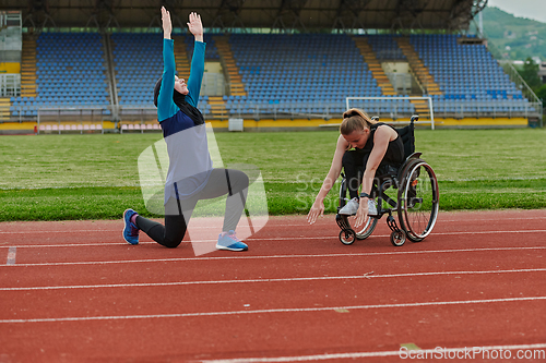 Image of Two strong and inspiring women, one a Muslim wearing a burka and the other in a wheelchair stretching and preparing their bodies for a marathon race on the track