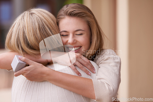 Image of I love you, mom. A daughter embracing her mother after receiving a gift.