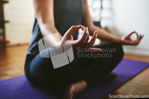 Image of Finding my balance. Cropped shot of an unrecognizable woman sitting on a yoga mat and meditating alone in her home.