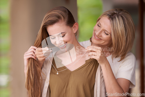 Image of I want you to have this.... A mother lovingly putting a necklace around her daughters neck.