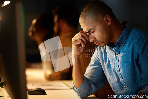 Image of When will I see the end of this.... Cropped shot of a young businessman looking stressed out while working late in an office.