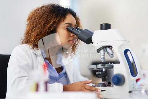 Image of Analysing microscopic data. Cropped shot of a young female scientist looking into a microscope.