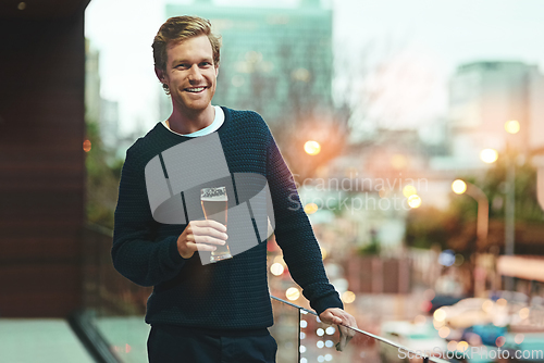 Image of Let the night begin. Portrait of a young man relaxing on a balcony while enjoying a beer.