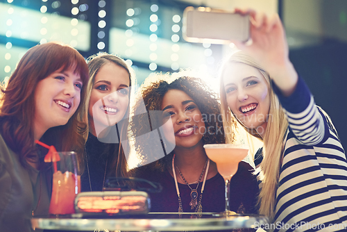 Image of Get your selfie faces ready. Shot of a group of happy friends taking a selfie while enjoying cocktails.