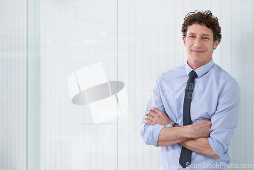 Image of He shows a lot of potential at work. Cropped shot of a young businessman standing in an office with his arms crossed.