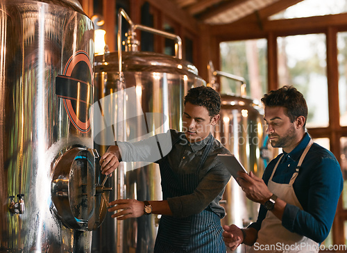 Image of Lets hope this batch is a good one. Shot of two young working men doing inspection of their beer making machinery inside of a beer brewery during the day.