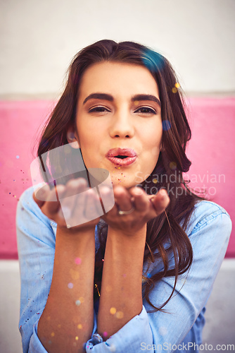 Image of There is nothing wrong with celebrating everyday. Portrait of a beautiful young woman blowing confetti outside.