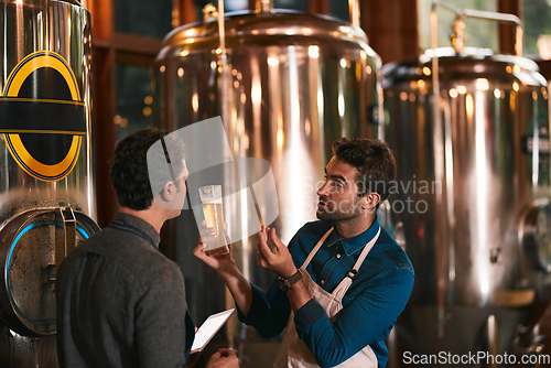 Image of Its all about the flavor. Shot of two young working men doing inspection of their beer making machinery inside of a beer brewery during the day.