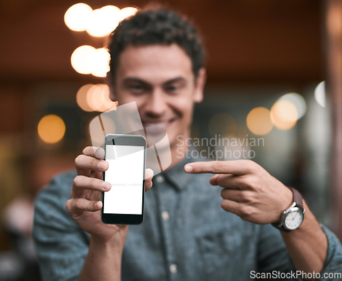 Image of Looks like were getting popular. Shot of a confident young man holding up a cellphone to the camera while standing inside of a beer brewery during the day.