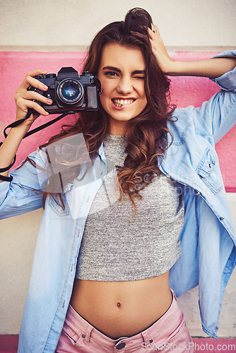 Image of Enjoy moments and capture memories. Portrait of a beautiful young woman holding a dslr camera and posing against a wall outside.