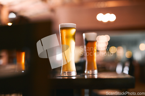 Image of Take the load of with a glass of beer. Shot of two glasses of beer standing on its own at a table inside of a beer brewery during the day.