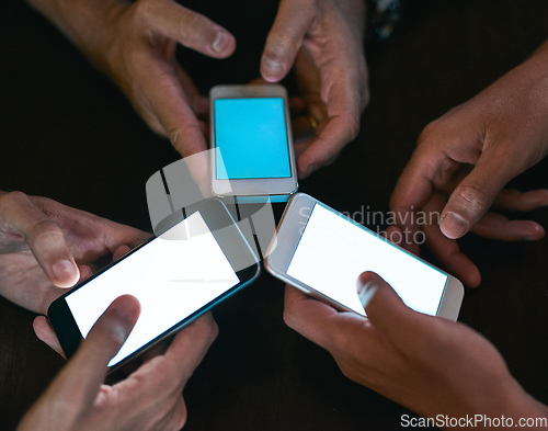 Image of All for one and one for all. High angle shot of three unrecognizable people seated in a circle at a table while browsing on their cellphones.