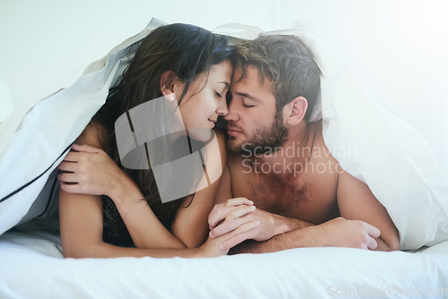 Image of I am more in love with you than ever. Shot of a young couple having an intimate moment under the covers.