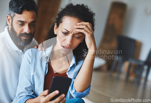 Image of I accidentally sent that picture to your mother. Shot of a dismayed couple receiving bad news via a smartphone at home.