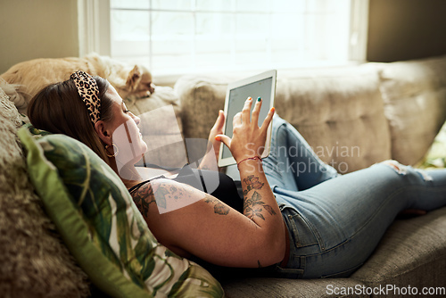 Image of With wifi comes a lot of relaxation. Shot of a young woman using a digital tablet on the sofa at home.