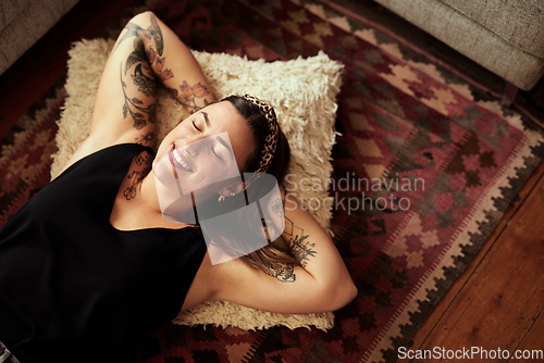 Image of Rest your way to happiness. Shot of a young woman relaxing on the floor of her living room at home.