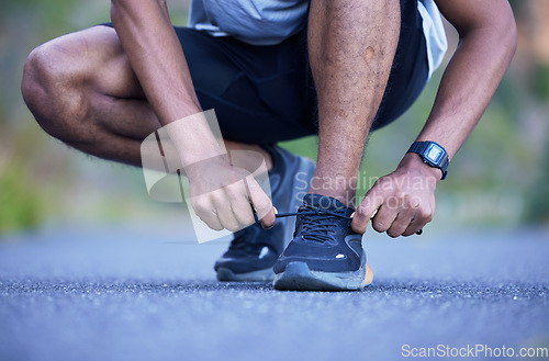 Image of Fitness, exercise and a man tying shoelace outdoor for run, workout or training performance. Closeup of athlete person or runner with running shoes on a road for cardio or health and wellness