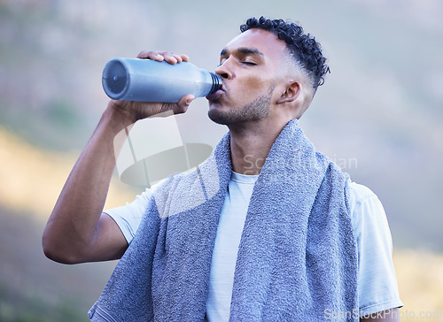 Image of Fitness, exercise and a man drinking water outdoor on a break or rest after run, workout or training. Tired athlete person or runner in nature with a bottle for thirst, cardio or health and wellness