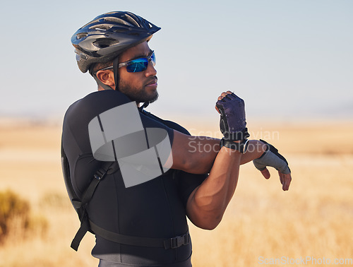 Image of Fitness, nature and man cyclist stretching arms for race, marathon or competition training. Sports, cycling and male athlete doing warm up exercise for health at an outdoor cardio workout by mountain