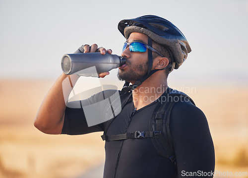 Image of Fitness, health and man cyclist drinking water at race, marathon or competition training. Sports, workout and thirsty male athlete with hydration for wellness at an outdoor cardio exercise in nature.