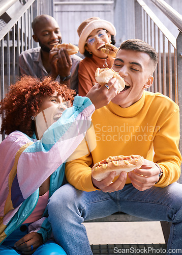 Image of Friends, city and feeding food outdoor for happiness, funny laugh and fun on stairs. Diversity, eating and gen z group of men and women with a hotdog on a date, adventure and freedom in urban town