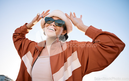 Image of Fashion, sunglasses and smile with a trendy woman outdoor on a blue sky for freedom, energy or style. Portrait, summer and clothes with a happy young model in an urban outfit while on vacation