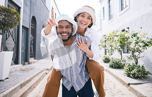 Image of Happy interracial couple, travel or piggyback in city on romantic date to play a fun outdoor game. Smile, pointing or excited black man carrying gen z woman or walking for urban sightseeing together