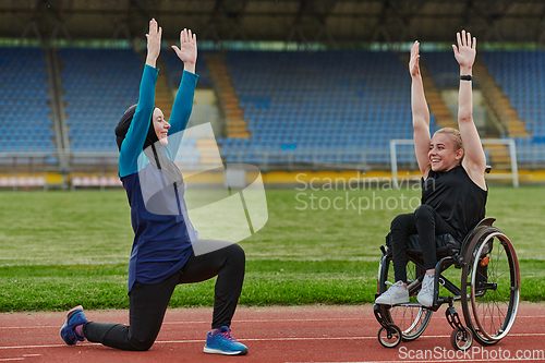 Image of Two strong and inspiring women, one a Muslim wearing a burka and the other in a wheelchair stretching and preparing their bodies for a marathon race on the track