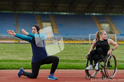 Image of Two strong and inspiring women, one a Muslim wearing a burka and the other in a wheelchair stretching and preparing their bodies for a marathon race on the track