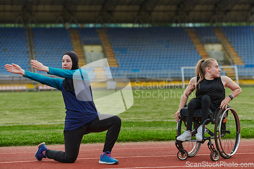 Image of Two strong and inspiring women, one a Muslim wearing a burka and the other in a wheelchair stretching and preparing their bodies for a marathon race on the track