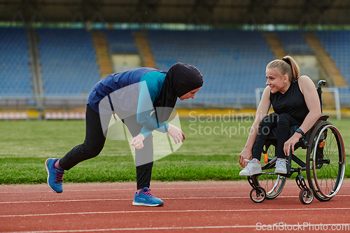 Image of Two strong and inspiring women, one a Muslim wearing a burka and the other in a wheelchair stretching and preparing their bodies for a marathon race on the track