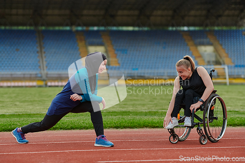 Image of Two strong and inspiring women, one a Muslim wearing a burka and the other in a wheelchair stretching and preparing their bodies for a marathon race on the track