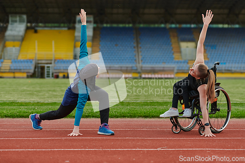 Image of Two strong and inspiring women, one a Muslim wearing a burka and the other in a wheelchair stretching and preparing their bodies for a marathon race on the track