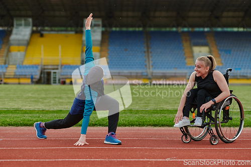 Image of Two strong and inspiring women, one a Muslim wearing a burka and the other in a wheelchair stretching and preparing their bodies for a marathon race on the track