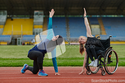 Image of Two strong and inspiring women, one a Muslim wearing a burka and the other in a wheelchair stretching and preparing their bodies for a marathon race on the track