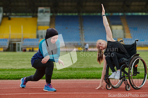 Image of Two strong and inspiring women, one a Muslim wearing a burka and the other in a wheelchair stretching and preparing their bodies for a marathon race on the track